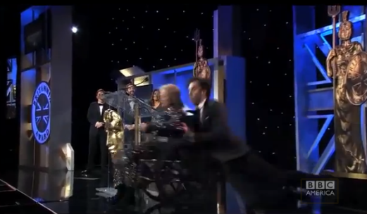 Watch Sasha Baron Cohen Push an Old (Stunt) Woman off the Stage at the Britannia Awards